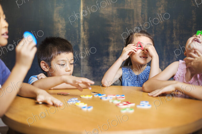 A group of children in school. Two boys and two girls holding up alphabet letters.