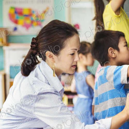 A group of children writing on the chalkboard with their teacher.