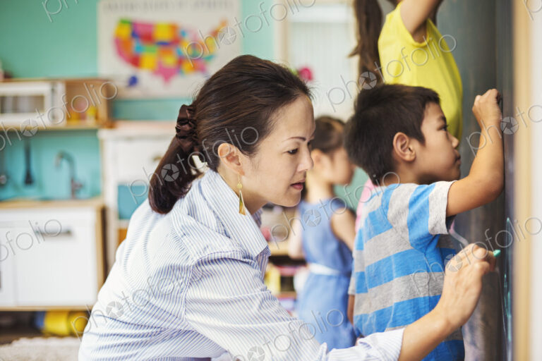 A group of children writing on the chalkboard with their teacher.