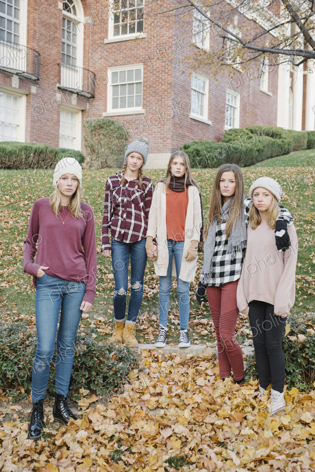 A group of five teenage girls outdoors in woolly hats and scarves.