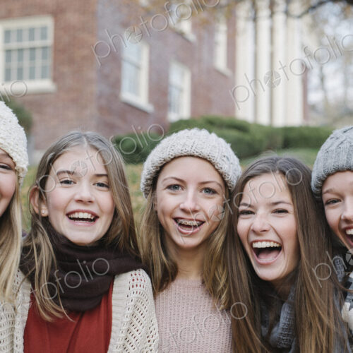 A group of five teenage girls outdoors in woolly hats and scarves. A group of five teenage girls outdoors in woolly hats and scarves.