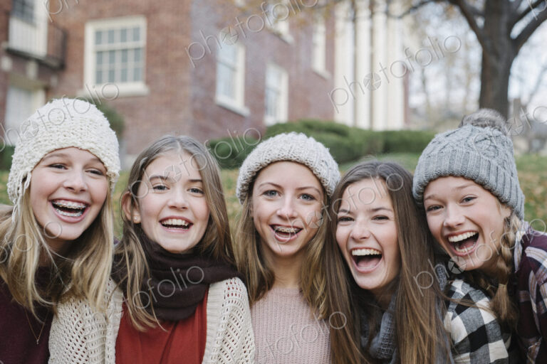 A group of five teenage girls outdoors in woolly hats and scarves.