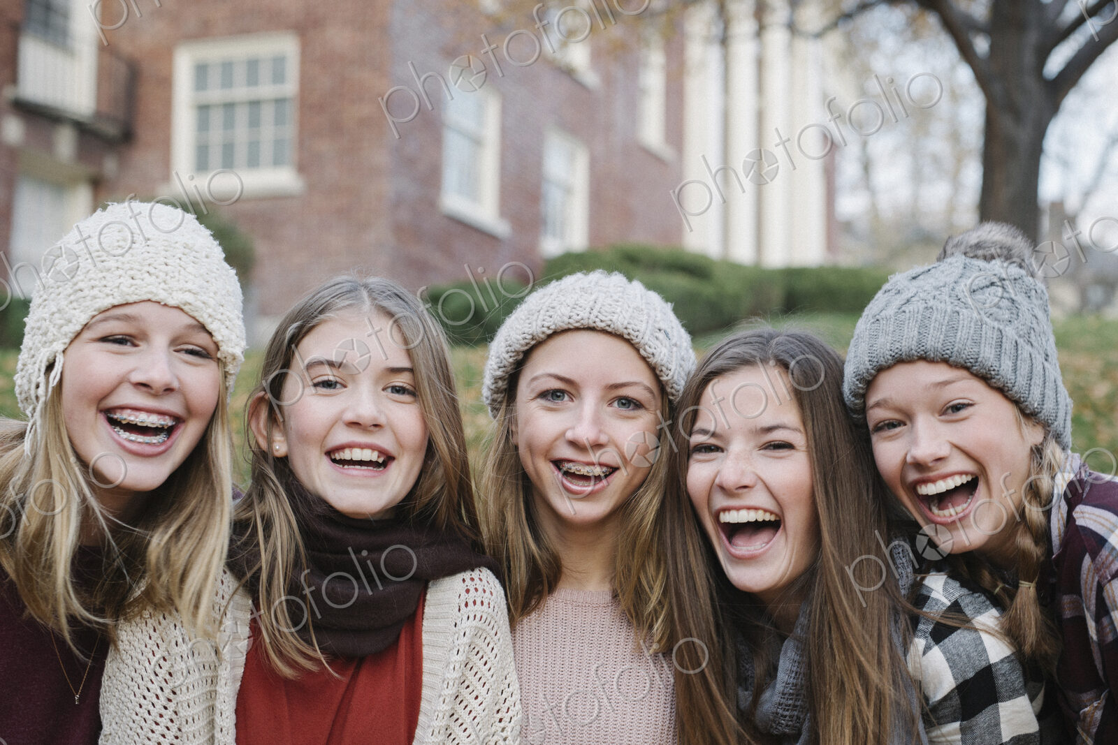 A group of five teenage girls outdoors in woolly hats and scarves.
