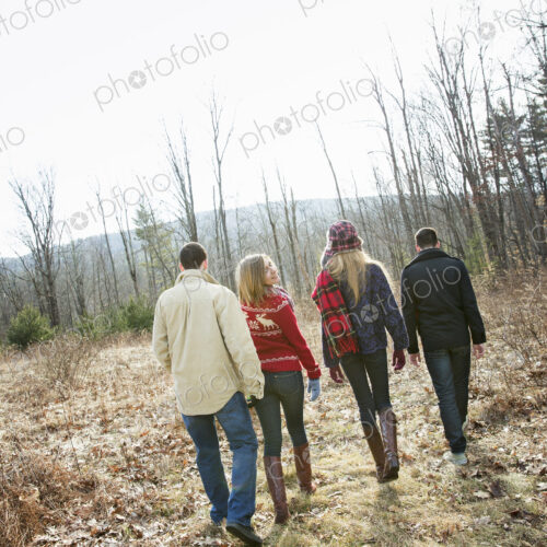 A group of four people walking through woodland on a winter day. Two men and two women. A group of four people walking through woodland on a winter day. Two men and two women.