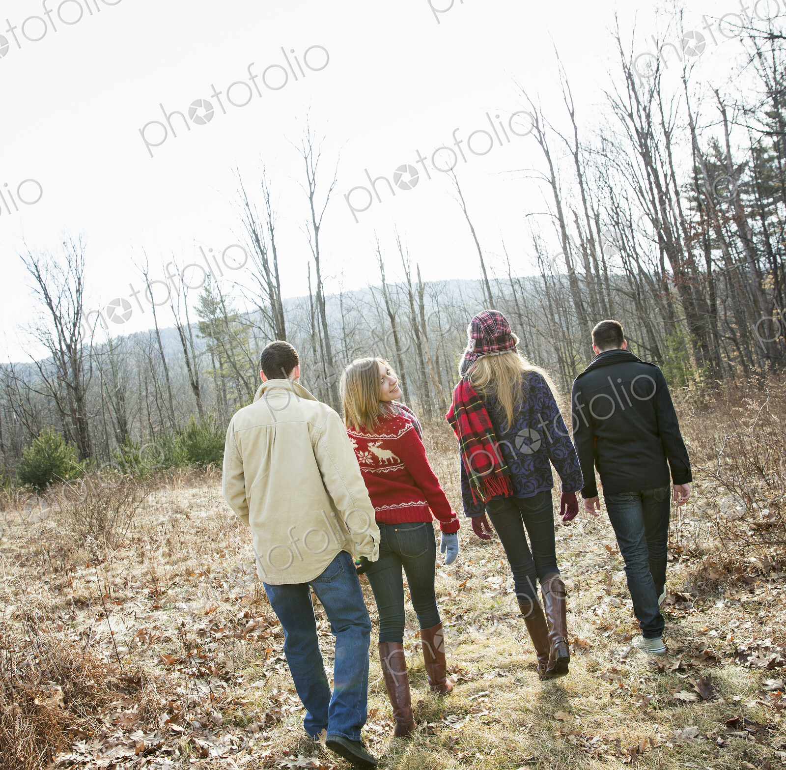 A group of four people walking through woodland on a winter day. Two men and two women.