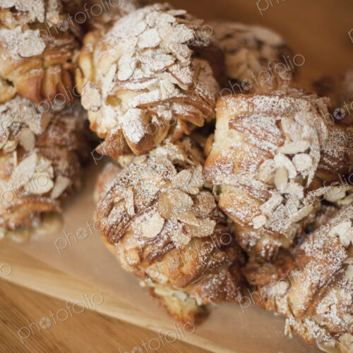 A group of fresh baked almond croissants, with icing sugar dusting. Organic party food… A group of fresh baked almond croissants, with icing sugar dusting. Organic party food…