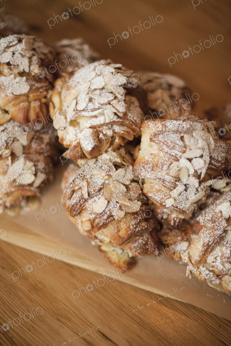 A group of fresh baked almond croissants, with icing sugar dusting. Organic party food…