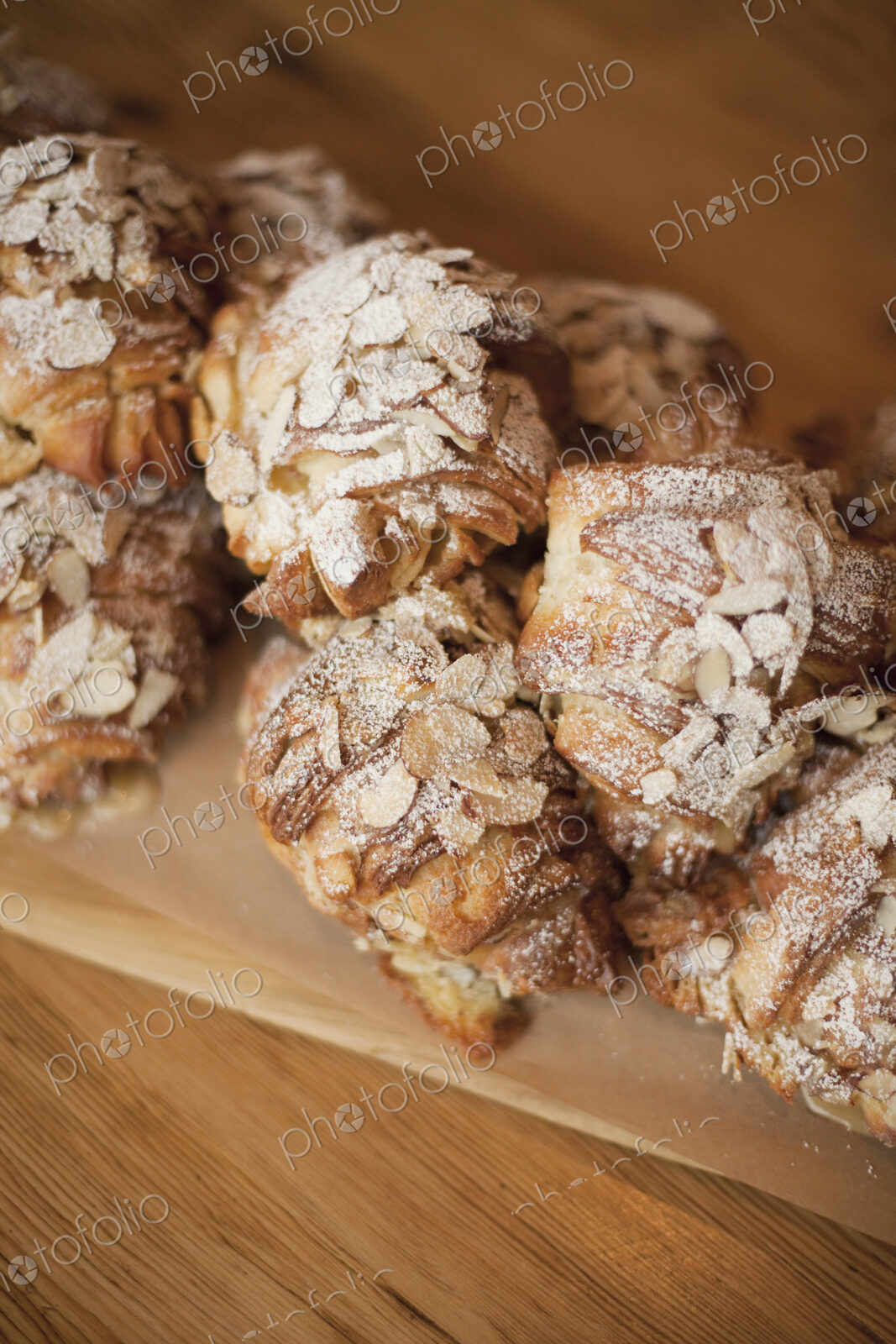A group of fresh baked almond croissants, with icing sugar dusting. Organic party food…