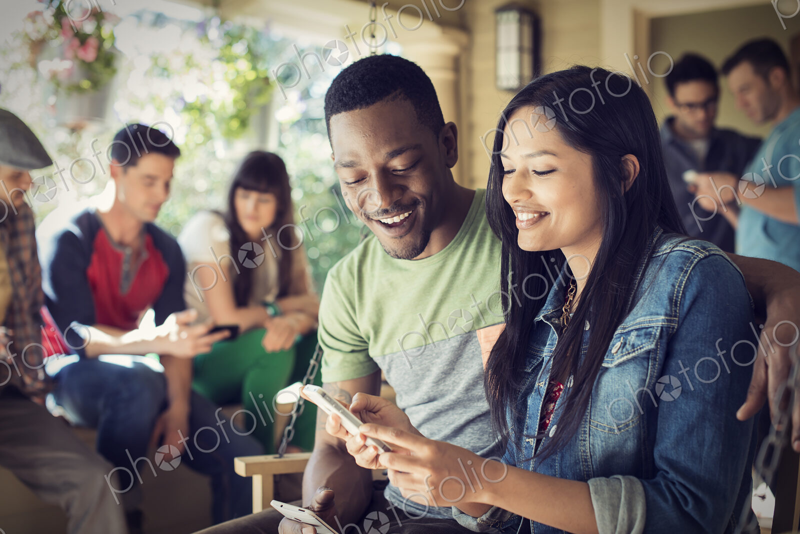 A group of friends, men and women at a house party, a woman holding a smart phone.
