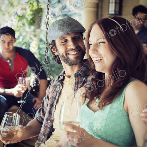 A group of friends, men and women at a house party drinking wine.