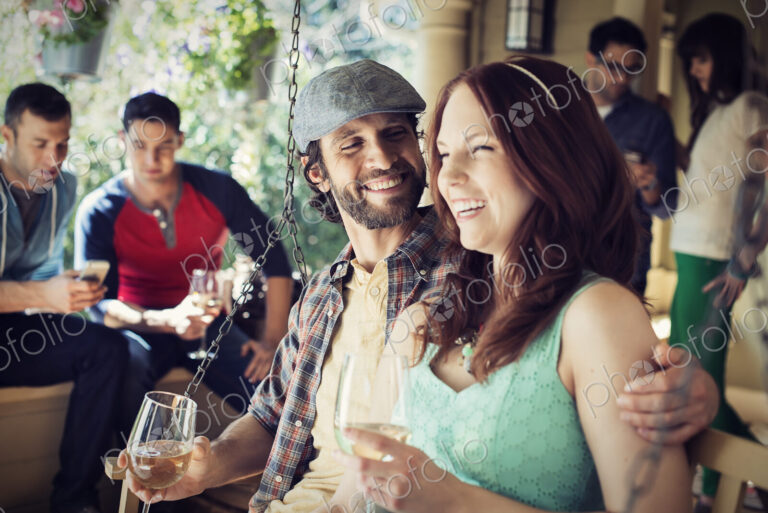 A group of friends, men and women at a house party drinking wine.
