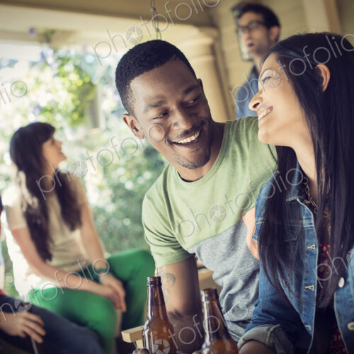 A group of friends, men and women at a house party drinking wine.