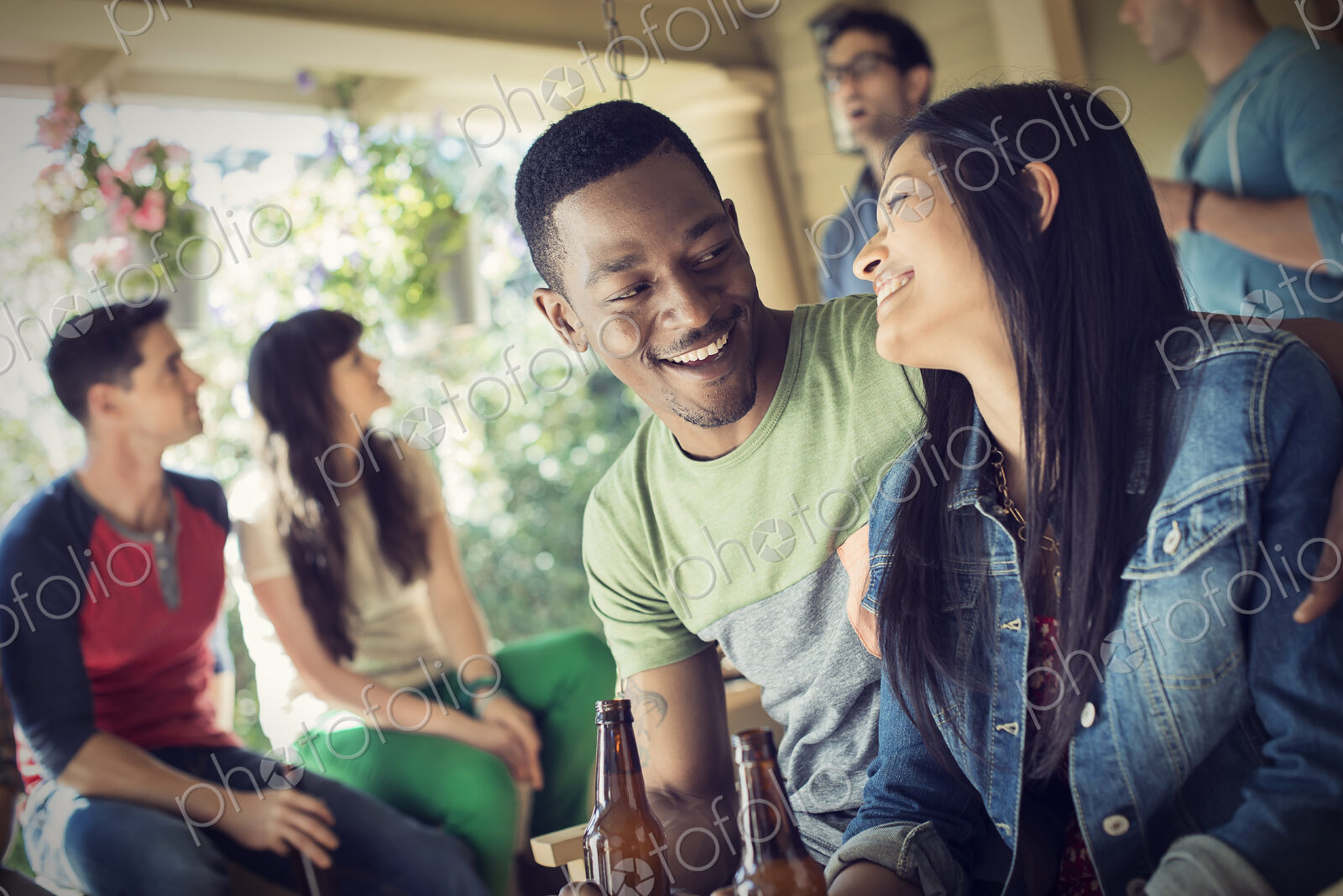 A group of friends, men and women at a house party drinking wine.