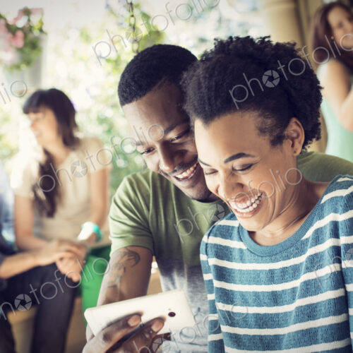 A group of friends, men and women at a house party. A cpuple taking a selfie.