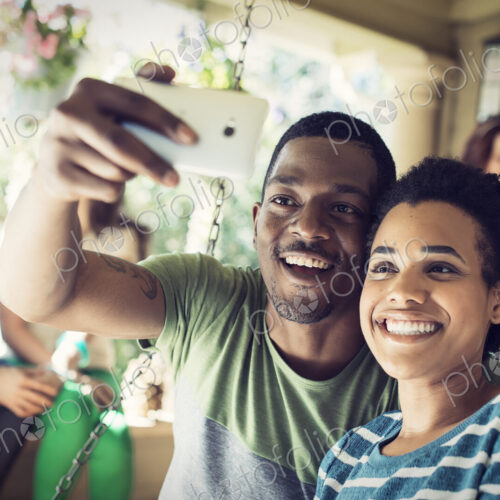 A group of friends, men and women at a house party. A cpuple taking a selfie.