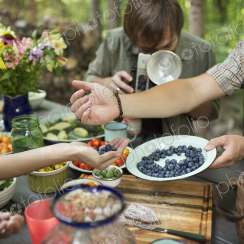 A group of friends outdoors sharing dishes of fresh fruits and salads. A group of friends outdoors sharing dishes of fresh fruits and salads.