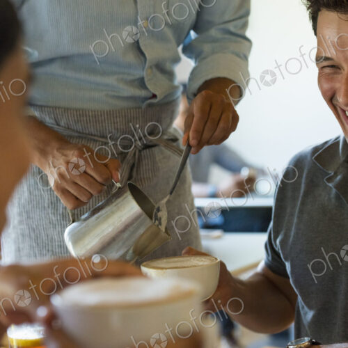 A group of men and women in a cafe, eating and drinking and enjoying each other's company. A group of men and women in a cafe, eating and drinking and enjoying each other's company.