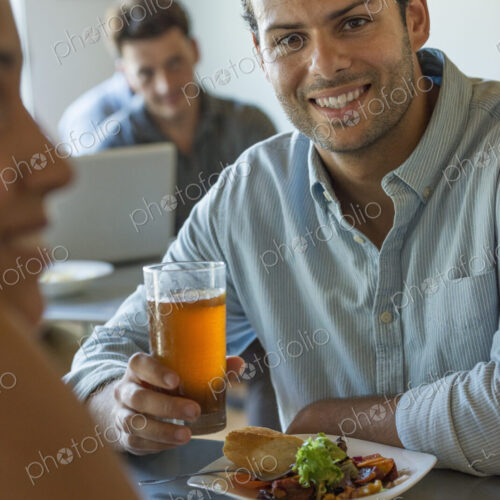 A group of men and women in a cafe, eating and drinking and enjoying each other's company. A group of men and women in a cafe, eating and drinking and enjoying each other's company.