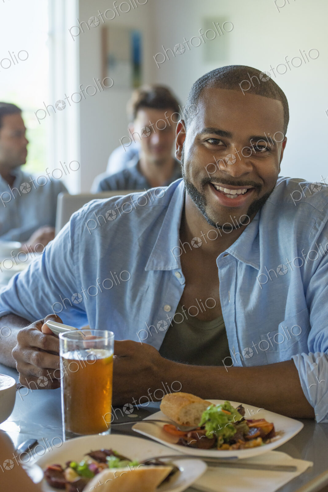 A group of men and women in a cafe, eating and drinking and enjoying each other’s company.