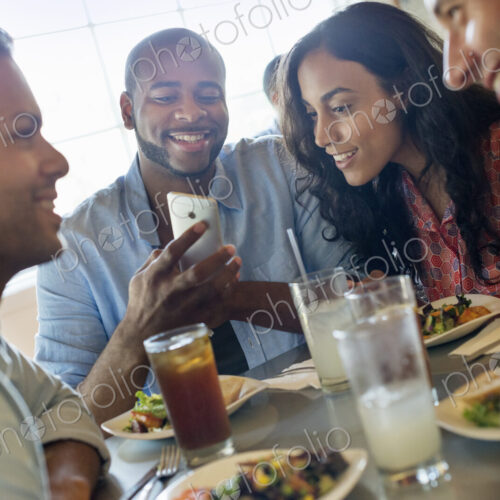 A group of men and women in a cafe, having drinks and enjoying each other's company.