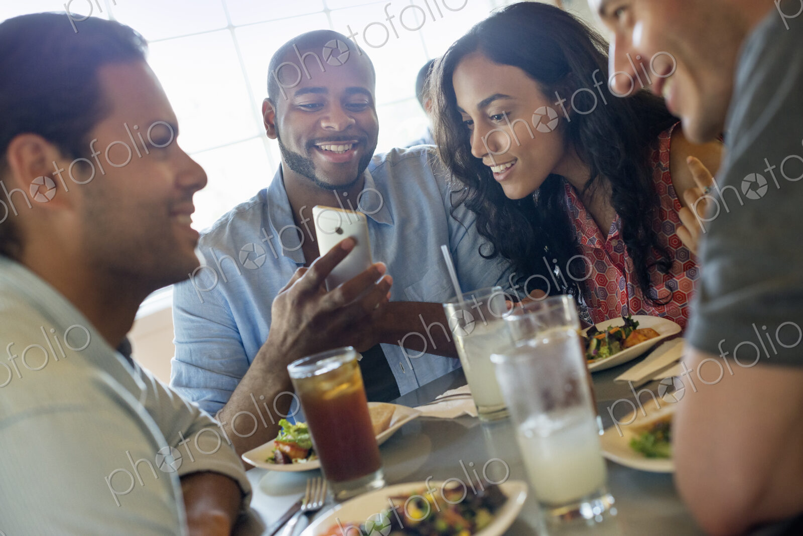 A group of men and women in a cafe, having drinks and enjoying each other’s company.