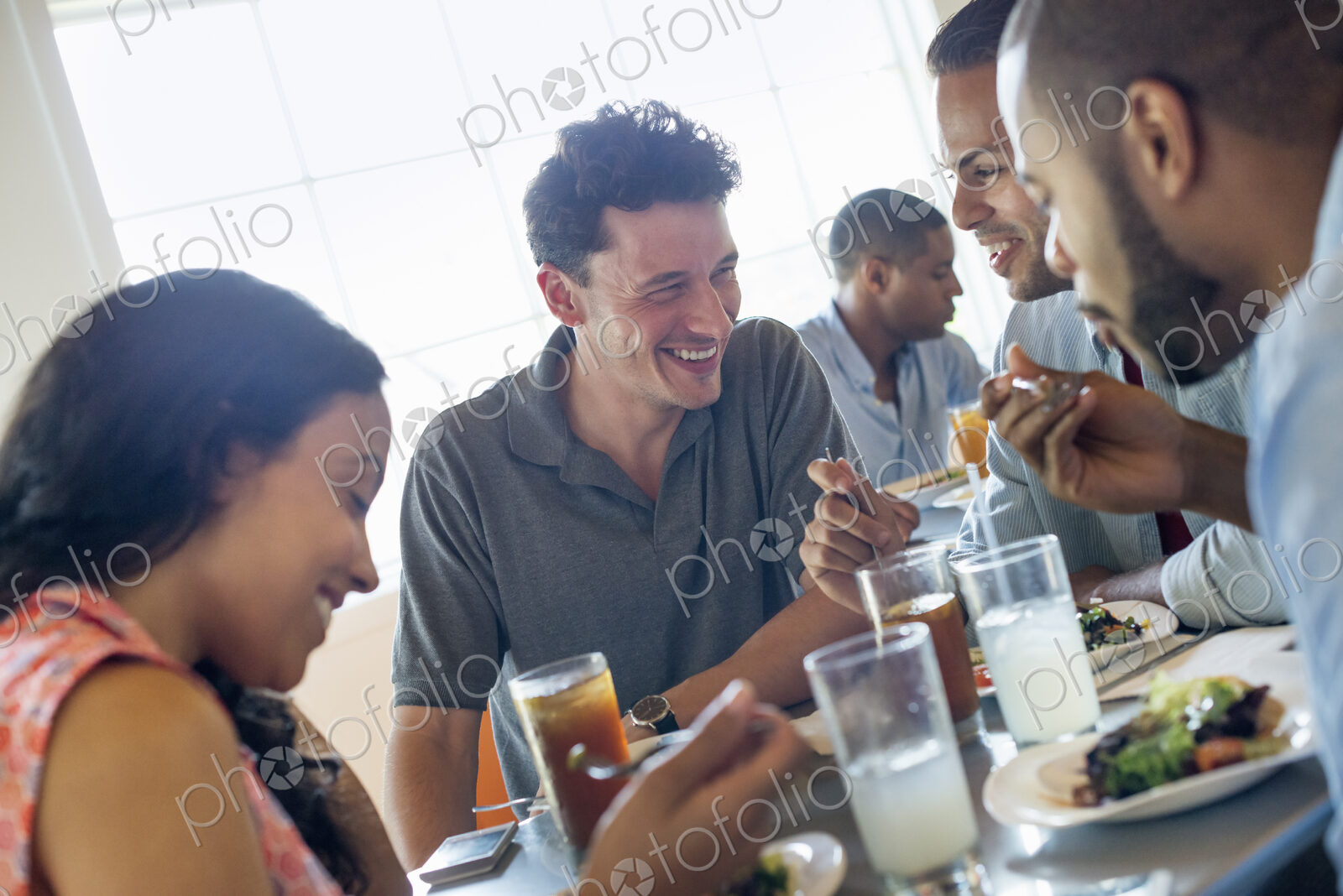 A group of men and women in a cafe, having drinks and enjoying each other’s company.