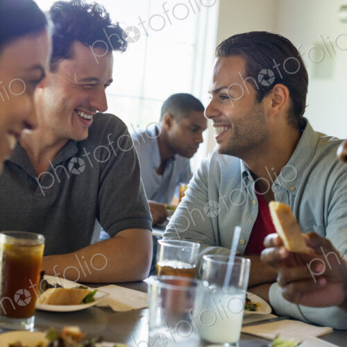 A group of men and women in a cafe, having drinks and enjoying each other's company.