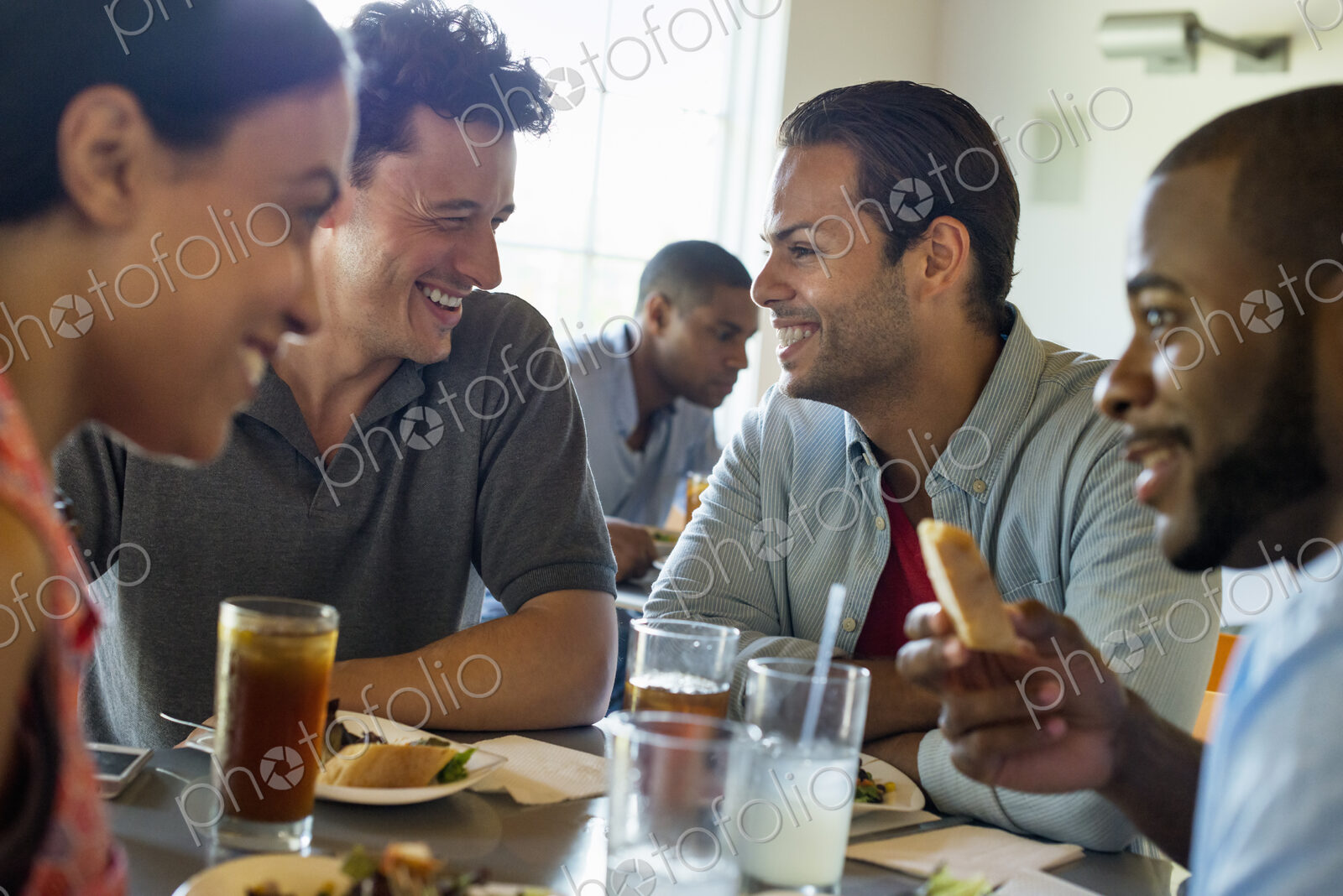 A group of men and women in a cafe, having drinks and enjoying each other’s company.