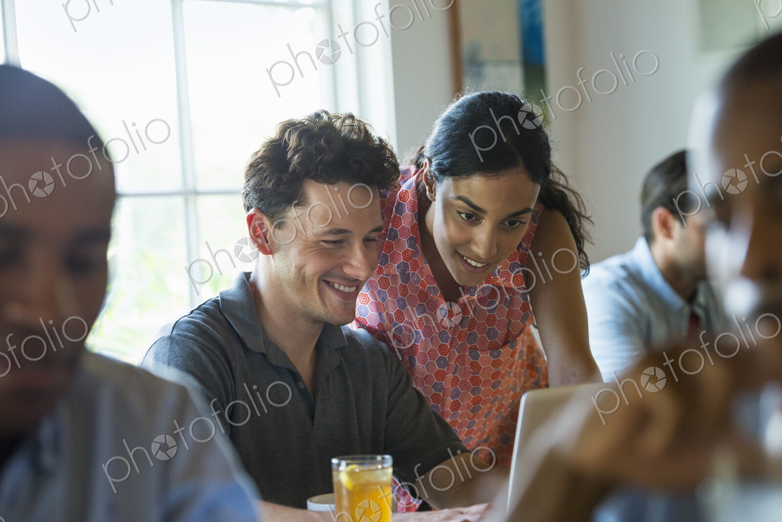 A group of men and women in a cafe, having drinks and enjoying each other’s company.