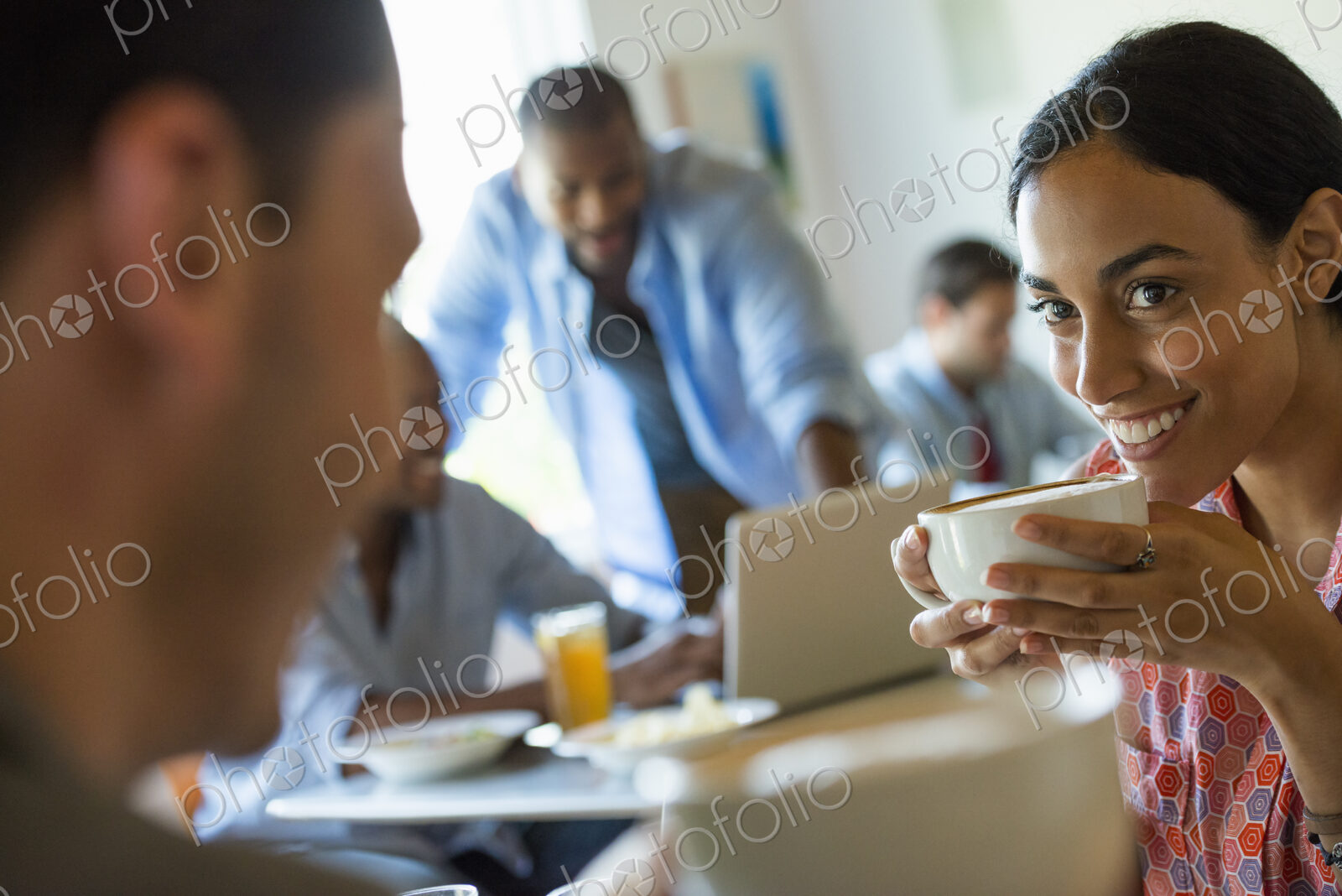 A group of men and women in a cafe, having drinks and enjoying each other’s company.