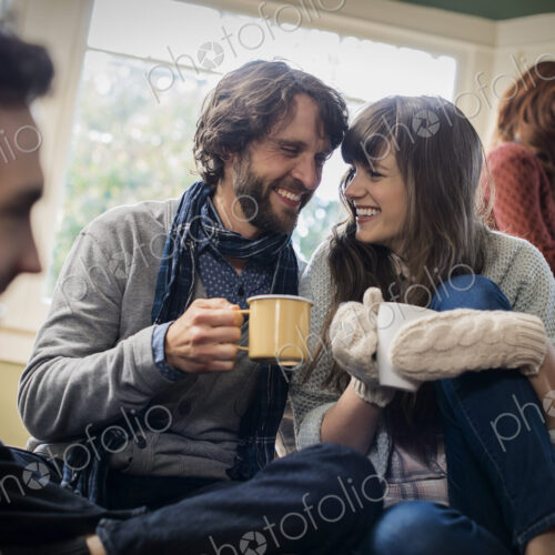 A group of men and women warming up with hot drinks.