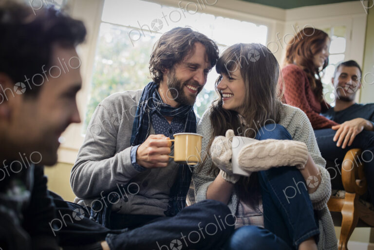 A group of men and women warming up with hot drinks.