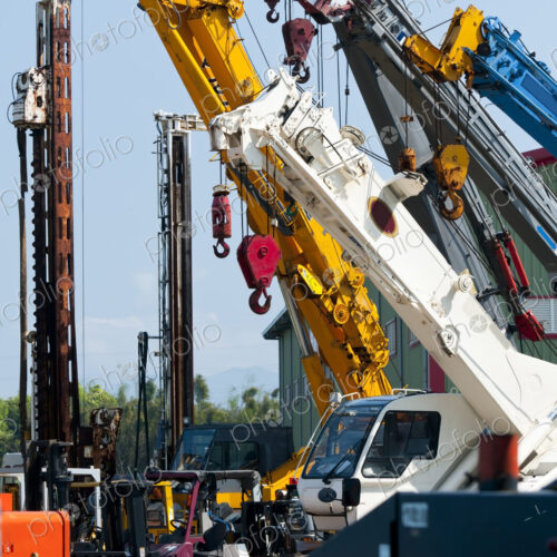 A group of mobile cranes with hooks and pulleys, dockyard lifting equipment.