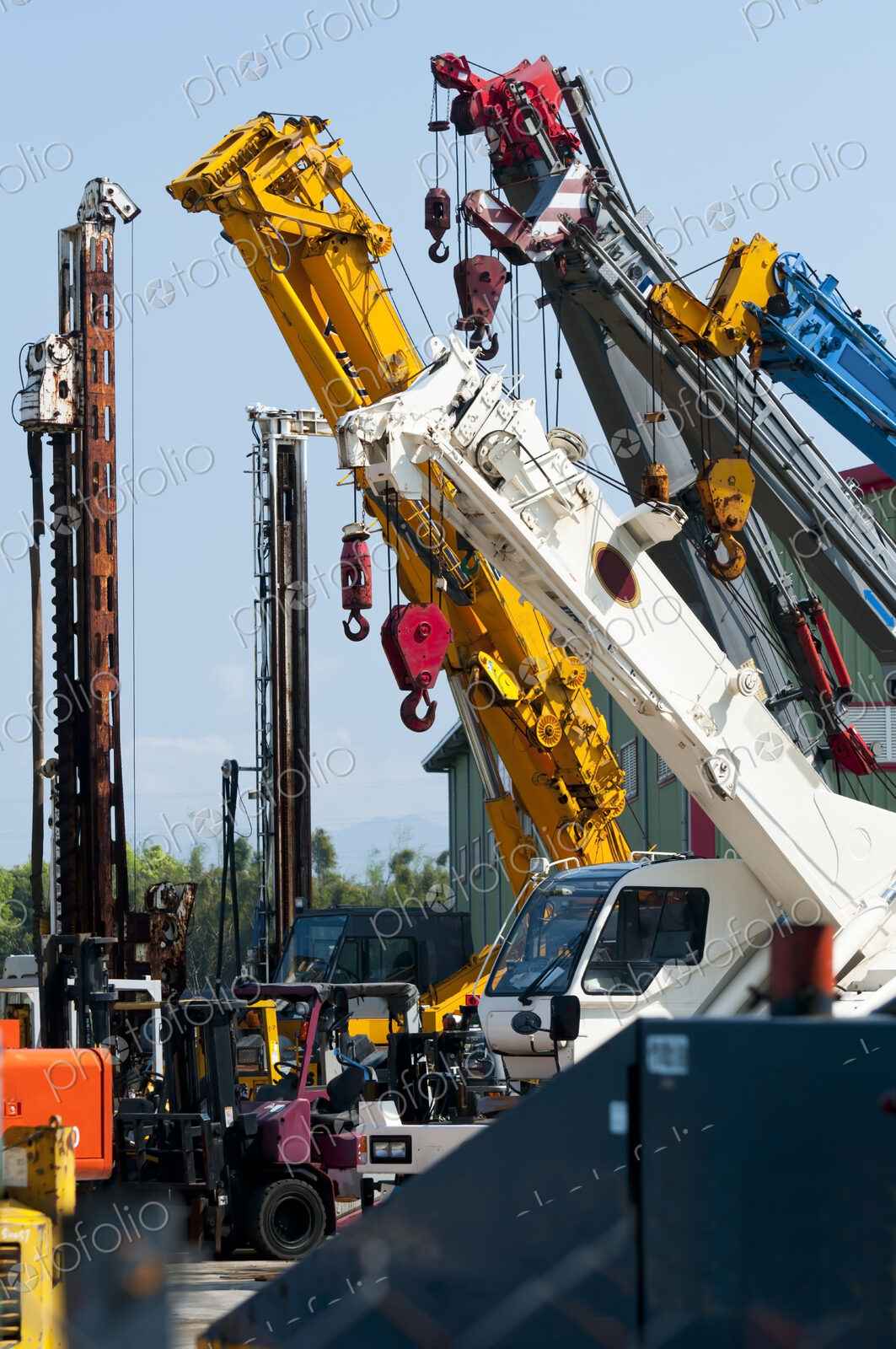 A group of mobile cranes with hooks and pulleys, dockyard lifting equipment.