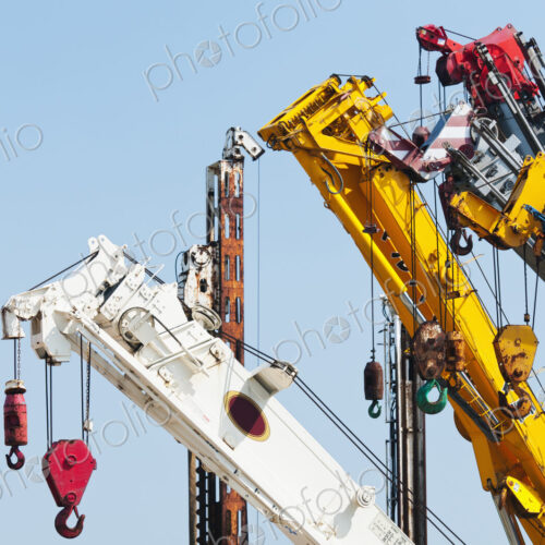 A group of mobile cranes with hooks and pulleys, dockyard lifting equipment.