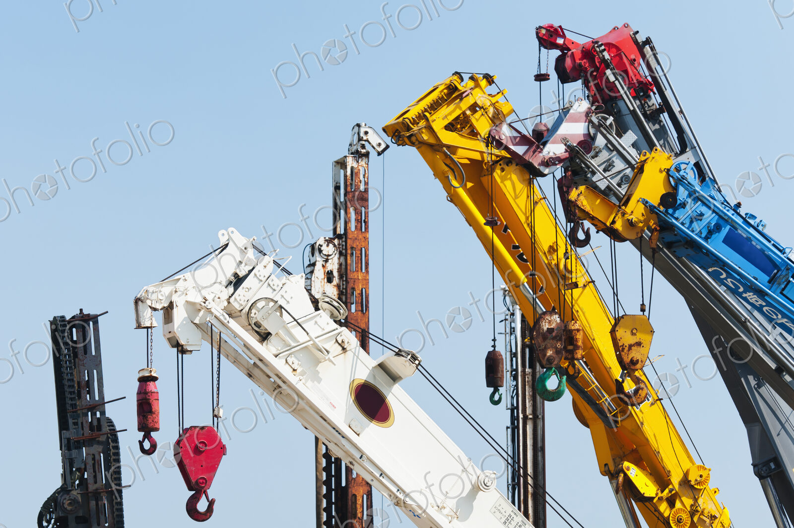 A group of mobile cranes with hooks and pulleys, dockyard lifting equipment.