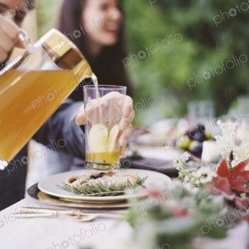 A group of people around a table in a garden. A celebration meal, with table settings…