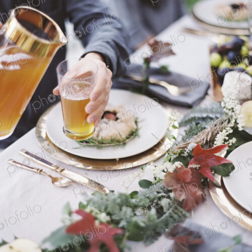 A group of people around a table in a garden. A celebration meal, with table settings…