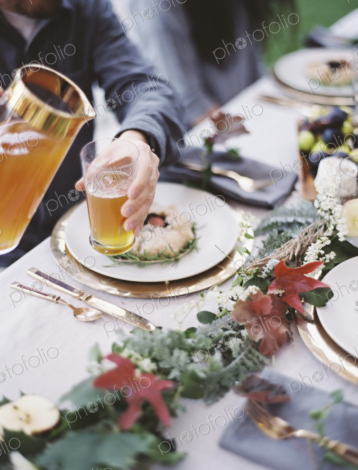 A group of people around a table in a garden. A celebration meal, with table settings…