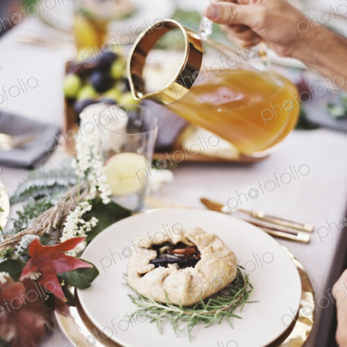 A group of people around a table in a garden. A celebration meal, with table settings…