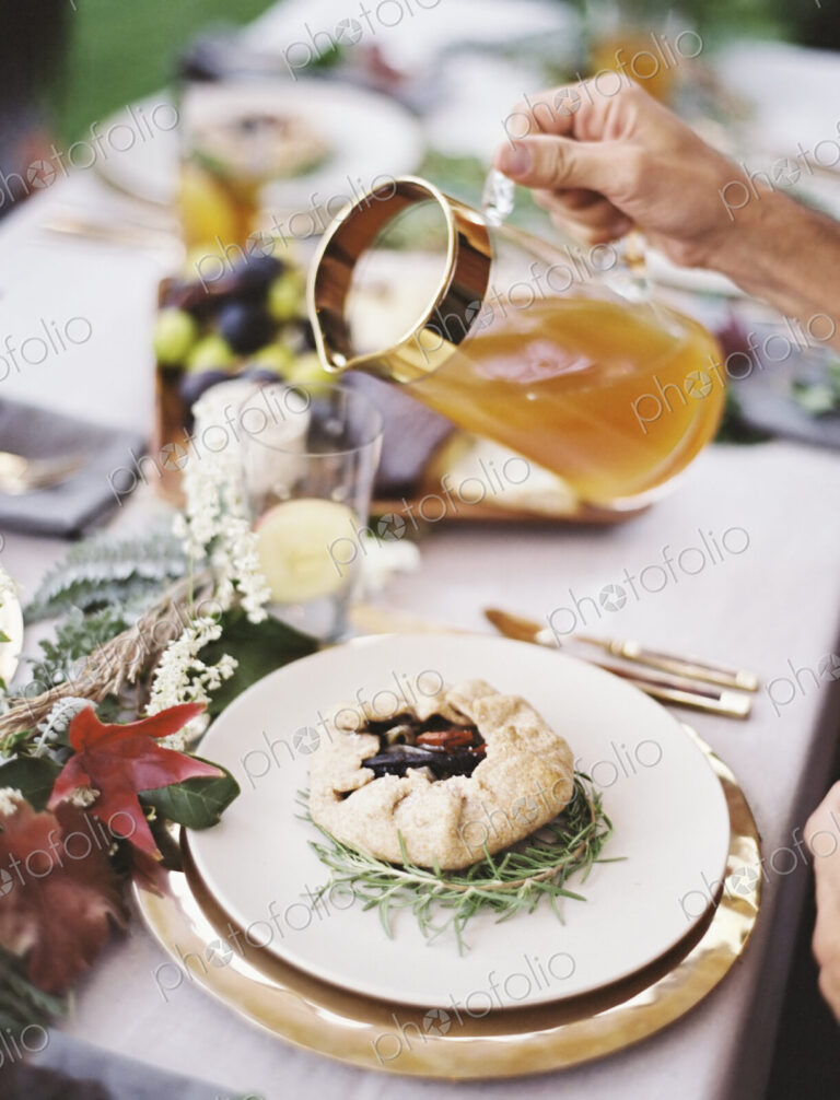 A group of people around a table in a garden. A celebration meal, with table settings…