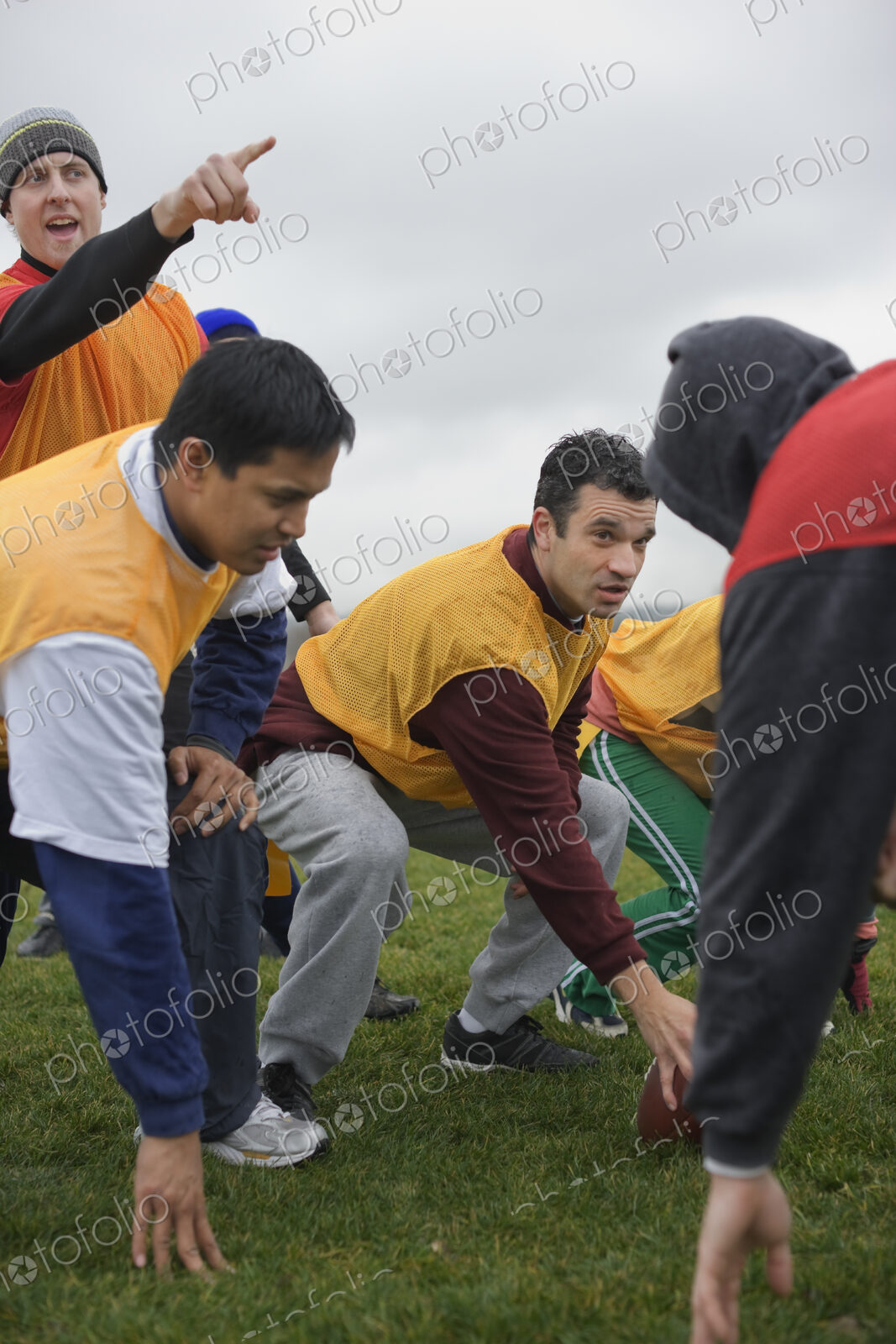 A group of people crouching, one playing quarterback for an non-contact flag football…
