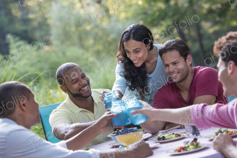 A group of people having a meal outdoors, a picnic. Men and women.