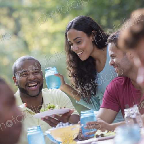 A group of people having a meal outdoors, a picnic. Men and women. A group of people having a meal outdoors, a picnic. Men and women.