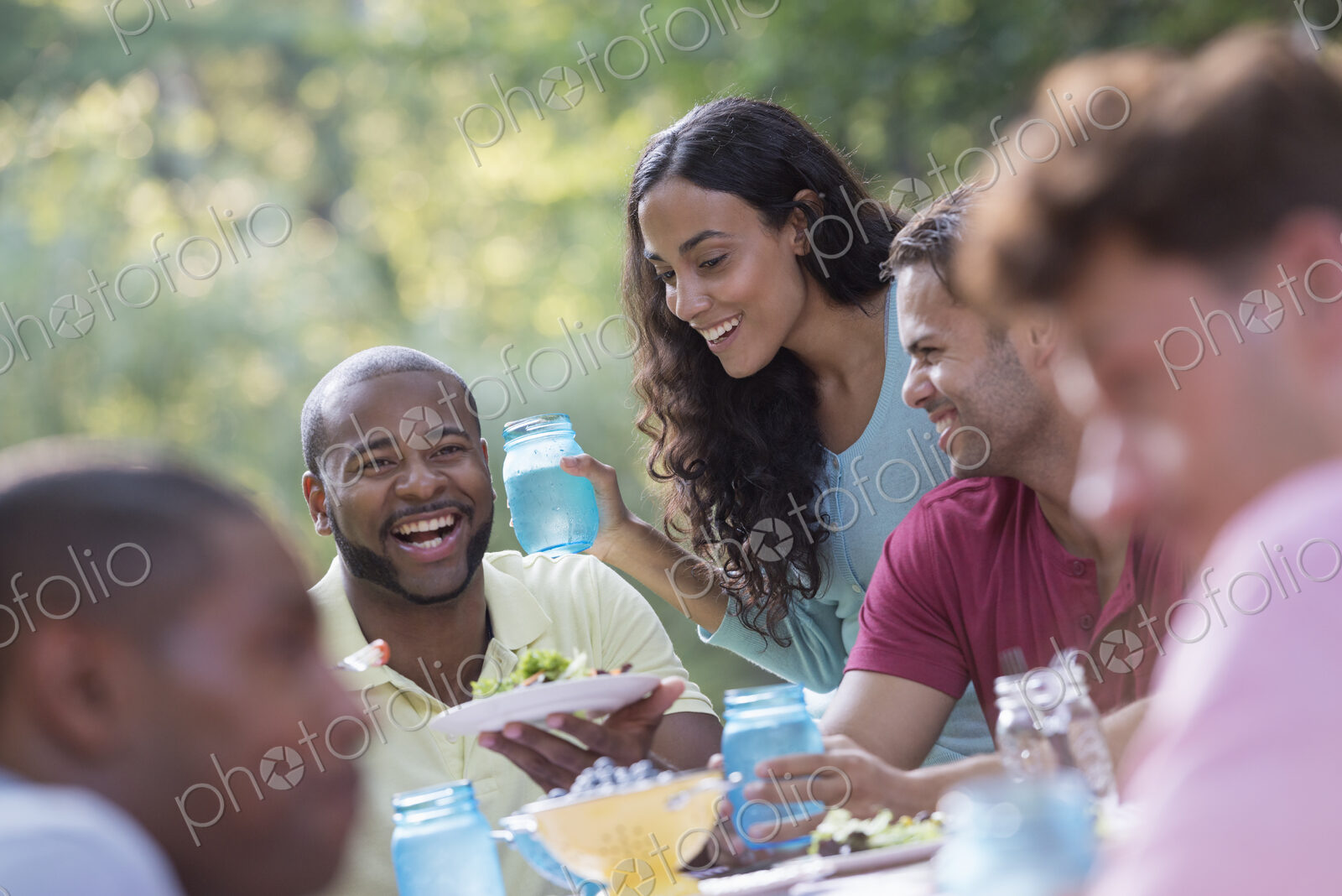A group of people having a meal outdoors, a picnic. Men and women.