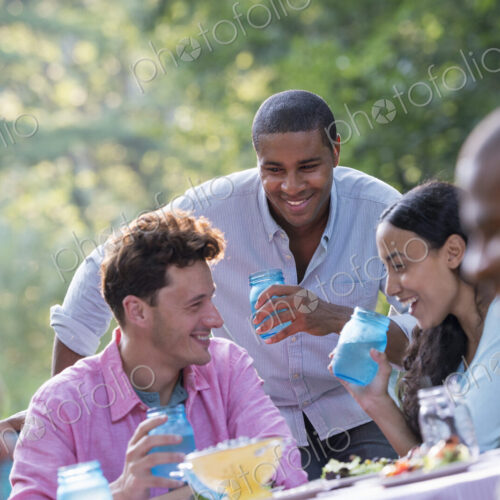 A group of people having a meal outdoors, a picnic. Men and women. A group of people having a meal outdoors, a picnic. Men and women.