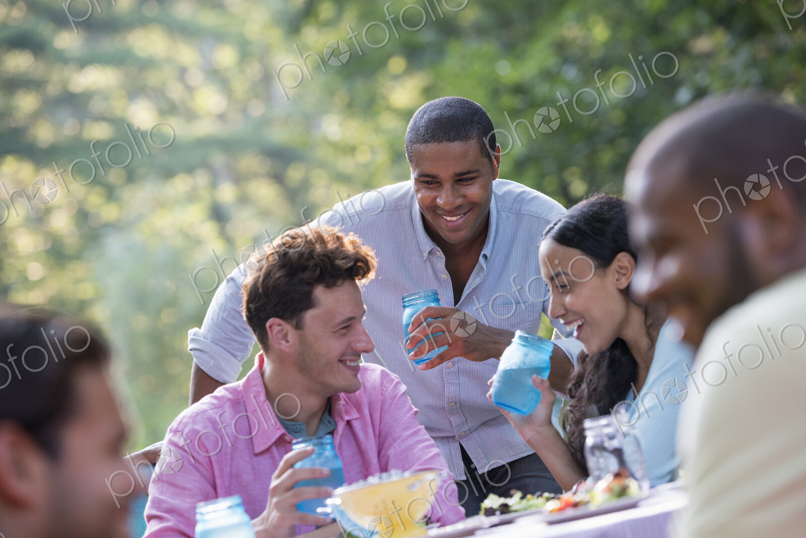 A group of people having a meal outdoors, a picnic. Men and women.