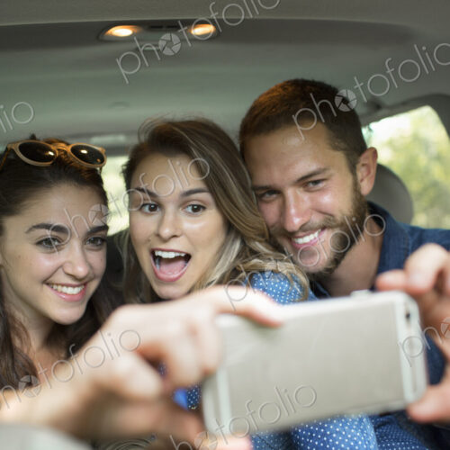 A group of people in a car, two women and a man taking a selfy. A group of people in a car, two women and a man taking a selfy.