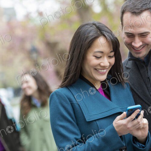 A group of people in a city park. A man in a grey coat, and a woman in a turquoise… A group of people in a city park. A man in a grey coat, and a woman in a turquoise…