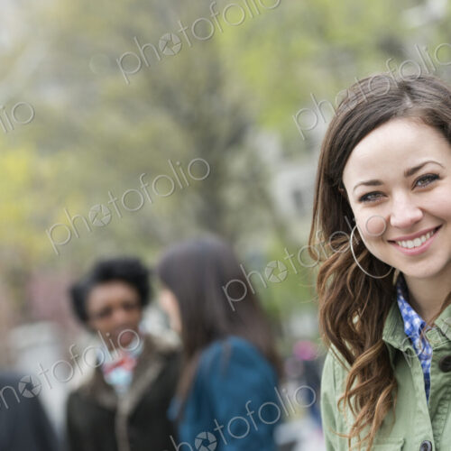A group of people in the park. A young woman in an open necked shirt, smiling and… A group of people in the park. A young woman in an open necked shirt, smiling and…